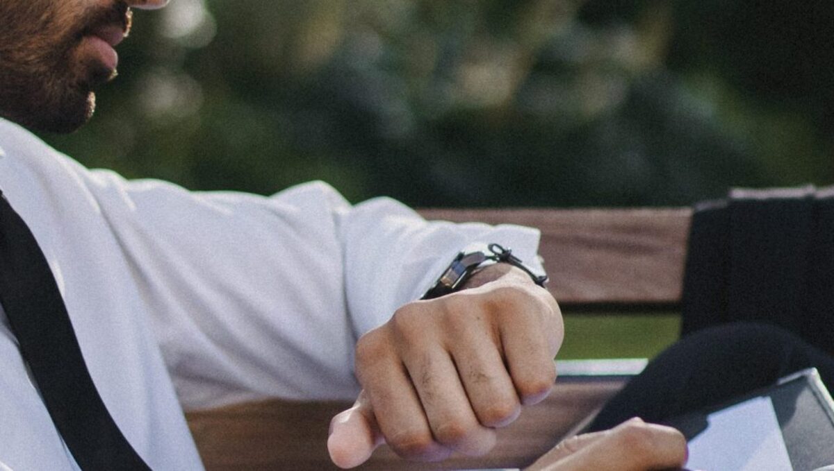 A man in a white long sleeves looking at his watch