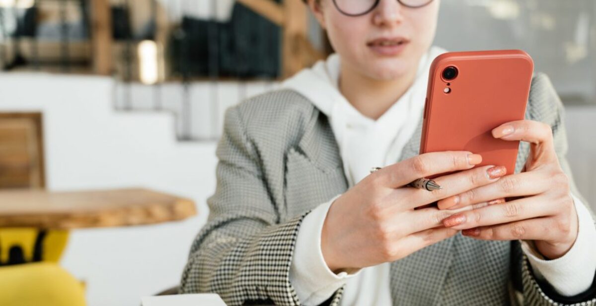 Crop businesswoman using smartphone in cafe