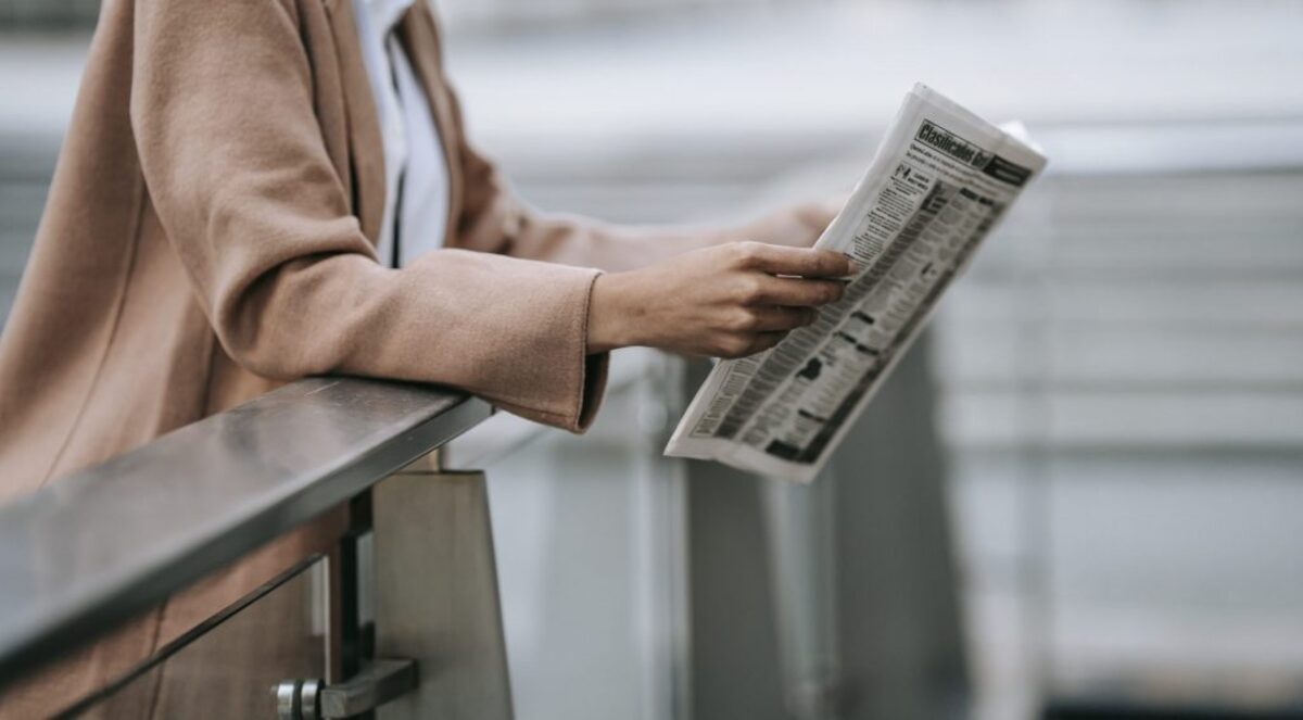 Unrecognizable black woman reading newspaper