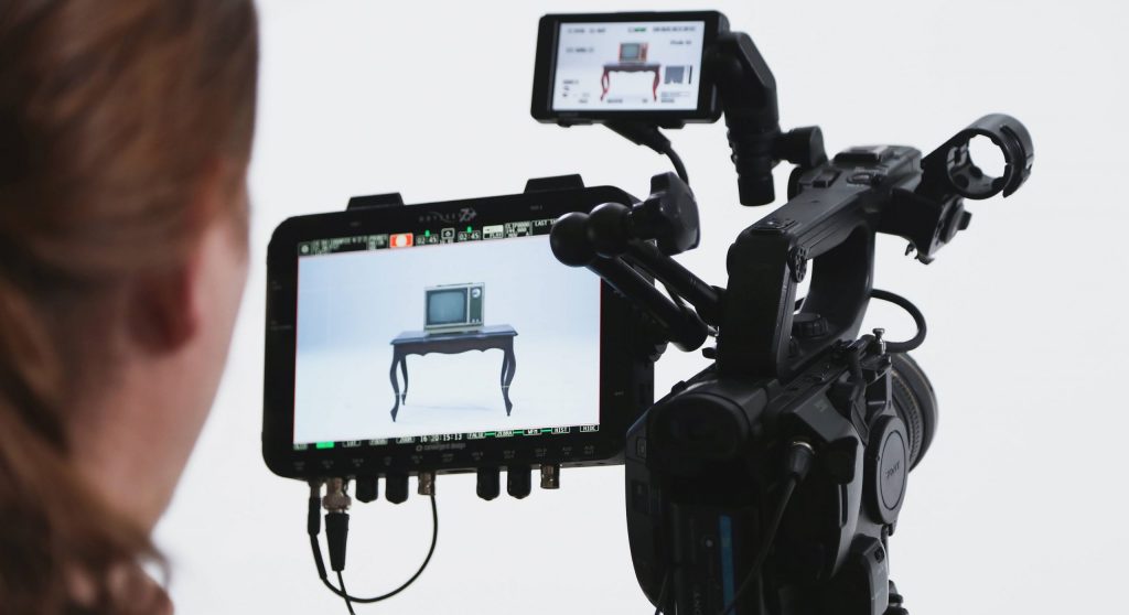 Woman on filmset holding a camera with monitor screen attachment