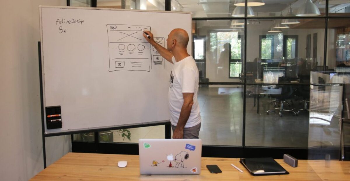 Concentrated male entrepreneur analyzing project standing near whiteboard in modern workspace