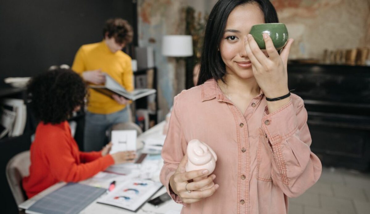 A woman in pink button up long sleeve shirt holding green ceramic cup