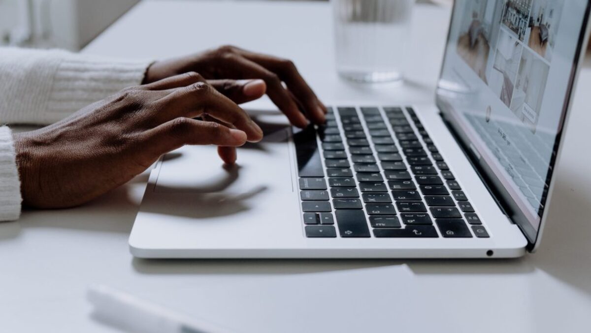 Person typing on a white laptop