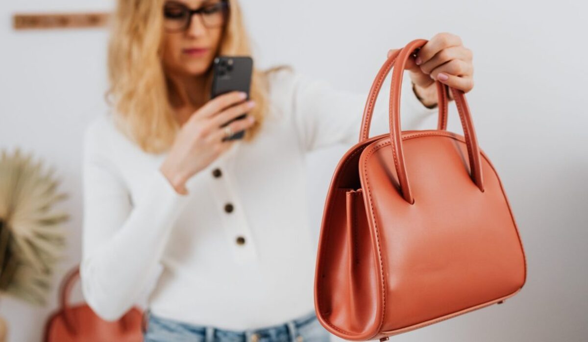 A woman in white long sleeves taking photos of a handbag