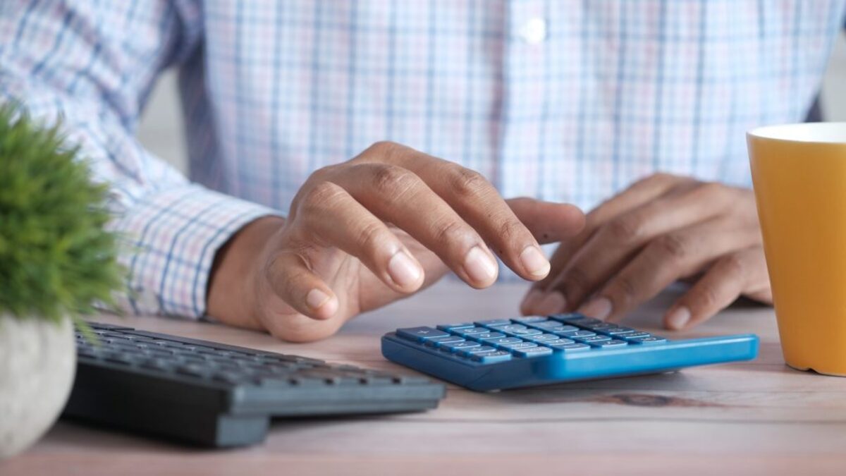 Close up of man hand using calculator.