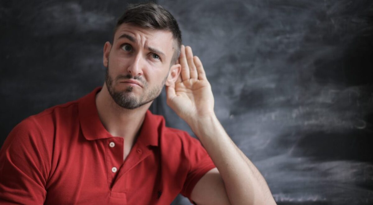 Man in red polo shirt sitting near chalkboard