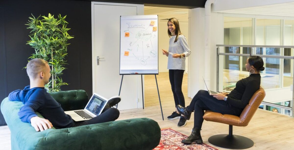 Two person listening to woman standing beside poster