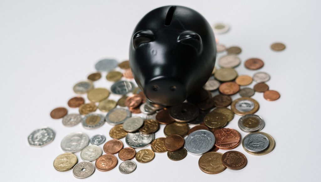 A black piggy bank in the middle of coins